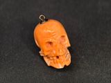 an orange carved skull pendant with a black cord on a black background
