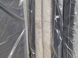 de nombreux matelas emballés dans du plastique, posés par terre
