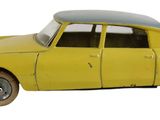 une petite voiture jaune posée sur une surface blanche, à côté d'un mur blanc