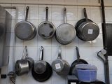 pots and pans are hanging on a wall in a kitchen