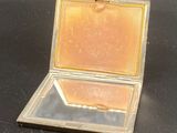 a small silver box with a mirror in it on a black surface