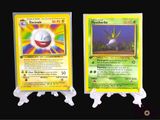 two pokemon cards are displayed on a black surface