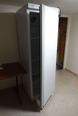 un réfrigérateur dans un coin d'une pièce où se trouve une table
