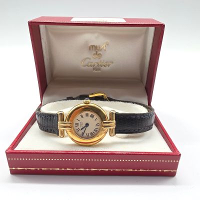 une photo d'une montre en or dans un coffret rouge, avec un bracelet noir