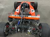 an orange race car that is parked in a parking lot
