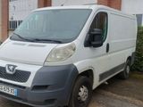 une petite camionnette blanche garée devant un bâtiment