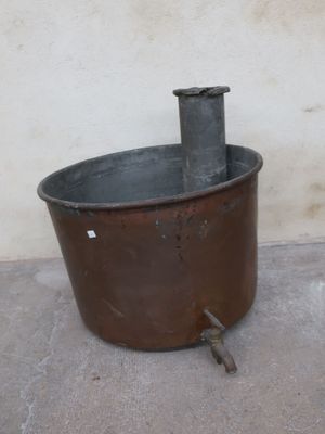 an old metal pot sitting on the ground next to a wall