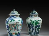 pair of chinese vases with painted figures on them on a table