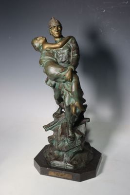 statue en bronze représentant une femme tenant un enfant sur un rocher