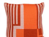 un gros plan d'un coussin orange et blanc sur fond blanc