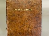 an old book sitting on top of a metal stand on a white surface
