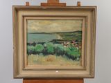 une peinture à l'huile représentant un paysage, posée sur un chevalet, avec une vue sur l'océan