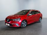 Une voiture rouge est garée dans une pièce aux murs blancs.