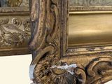 a mirror with a gold frame and a reflection of a man in the mirror