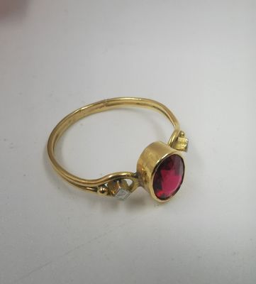 Gros plan sur une bague en or ornée d'une pierre rouge
