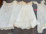 three white dresses are sitting on a bed next to each other