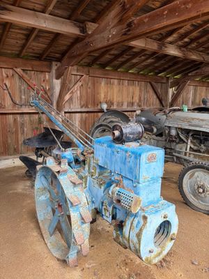 un tracteur bleu et un tracteur bleu à l'intérieur d'une grange
