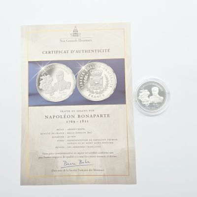 deux pièces d'argent et un certificat posés sur un fond blanc