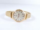 une image d'une montre-bracelet en or sur une surface blanche