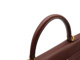 the handle of a brown leather briefcase with a gold clasp
