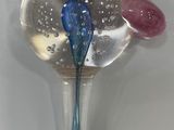 a glass spoon with a blue flower in it