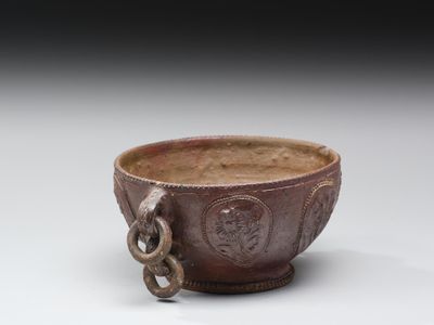un vieux bol marron entouré d'une chaîne, posé sur une surface blanche