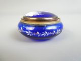 une boîte en verre bleue avec un couvercle doré posée sur une table