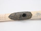 a wooden stick with a metal handle on a white surface