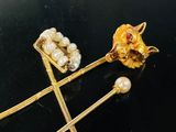deux épingles à cheveux dorées ornées de perles, posées sur un fond noir