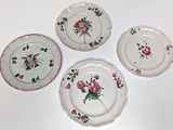 four plates with floral designs are arranged on a white surface
