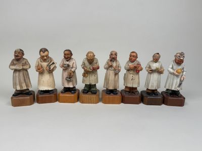 Plusieurs figurines représentant des personnes sont alignées sur des blocs de bois