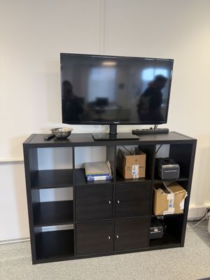 un meuble TV noir sur lequel est posée une télévision à écran plat