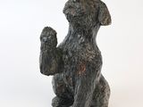 une statue représentant un chien assis sur une surface blanche