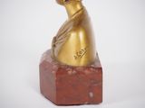 a gold statue of a woman sitting on a red marble block