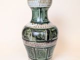 a green and white vase sitting on a white surface