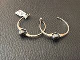 un gros plan sur une paire de boucles d'oreilles posées sur une surface en cuir