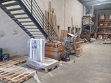 several pallets of wood sit in front of a staircase in a warehouse