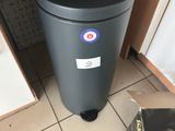 a black trash can sitting on the floor next to a person ' s shoes