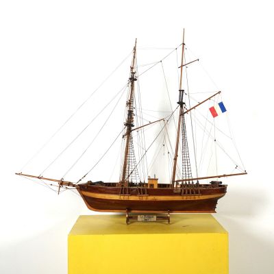 une maquette de voilier posée sur un socle jaune