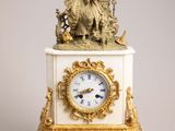 a white and gold clock with a statue on top of it