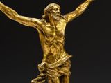 a gold statue of jesus on the cross on a marble base