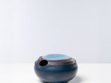 un bol bleu et noir posé sur une table blanche