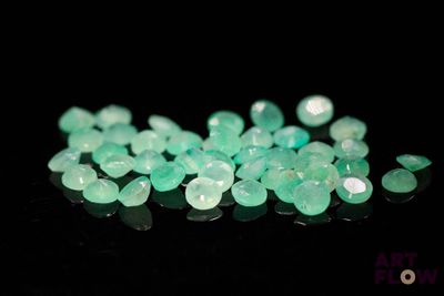 a close up of a pile of green stones on a black surface