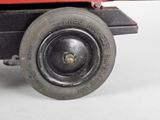 a red toy truck with a black wheel on a white surface