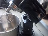 a black mixer with a metal bowl and a whisk attachment