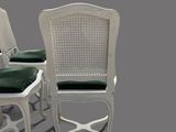 two white chairs with green cushions and a white cane back