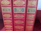 trois livres rouges sont alignés sur un tissu rouge