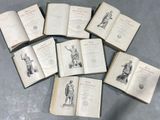several open books on a table with a statue in the middle of them