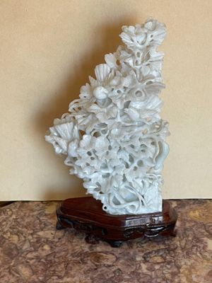 une sculpture blanche représentant des fleurs, posée sur un socle en bois