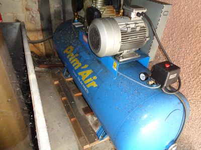 a blue air compressor sitting on the floor next to a wall